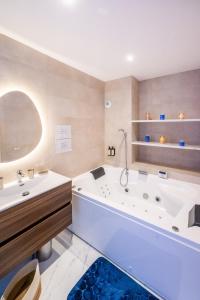 a bathroom with a large white tub and a sink at L'Escapade Indigo - Balnéo - Sauna in Tournefeuille