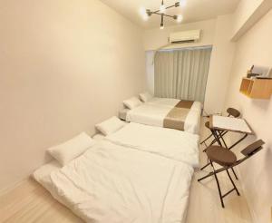 a small room with two beds and a desk at Stay min NAKAMURA in Nagoya