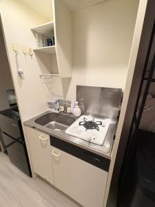 a small kitchen with a sink and a stove at Stay min NAKAMURA in Nagoya