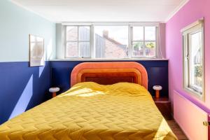 a bedroom with a bed with a yellow comforter at Hotel Domburg4you in Domburg