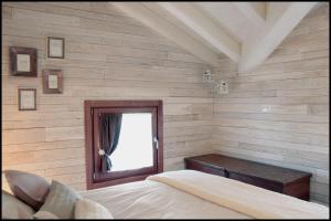 Casa Vacanze Borc dai Cucs في Faedis: غرفة نوم بجدران خشبية ونافذة وسرير