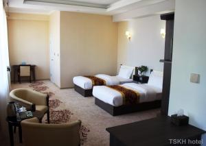 a hotel room with two beds and a chair at Tsetsenkhangai Hotel in Ulaanbaatar