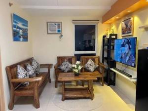 a living room with two chairs and a table and a television at Lis Urban Residence in Manila