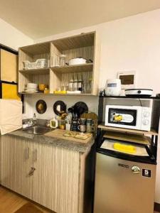 a small kitchen with a microwave and a refrigerator at Lis Urban Residence in Manila