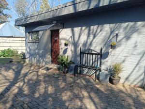 a house with a bench and potted plants on it at Lourette se Plek in Sannieshof