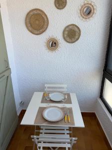 a white table with two chairs and plates on the wall at Apartment - Beach - AC - Private parking in Saint-Cyprien-Plage +4 photos