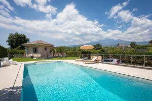 a swimming pool in front of a house at Tropical House in San Leonardello