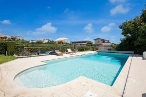 a swimming pool with two chairs in a yard at Tropical House in San Leonardello