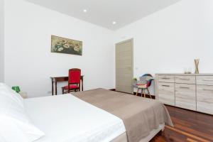 a white bedroom with a bed and a desk at Tropical House in San Leonardello +21 photos