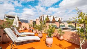 a balcony with chairs and potted plants on a building at Riad ABBASSIA Marrakech Première - Authentic Medina Experience in Marrakesh