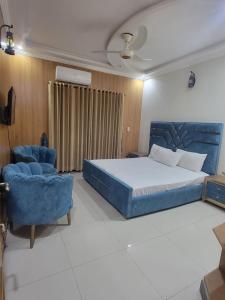 a bedroom with a bed and two blue chairs at INTOWN Hotel in Islamabad
