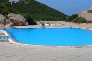 a large blue swimming pool with a mountain in the background at Appartamento "Hic et Nunc" in Costa Paradiso