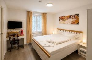 a bedroom with a bed and a desk with a television at Hotel Restaurant El Greco bei der Taffingsmühle in Saarlouis