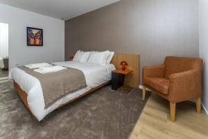 a bedroom with a bed and a chair at Refugio Moderno as Portas do Geres in Ponte da Barca