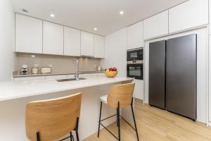 a kitchen with white cabinets and a stainless steel refrigerator at Refugio Moderno as Portas do Geres in Ponte da Barca