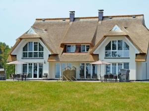 a large house with tables and umbrellas in front of it at Reethus am Strand - Haushälfte 1 mit Kamin, Sauna in Lobbe