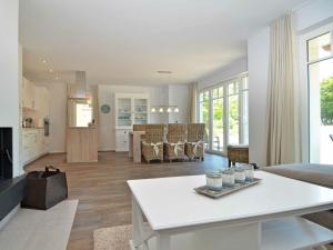 a living room with a white table and a kitchen at Reethus am Strand - Haushälfte 1 mit Kamin, Sauna in Lobbe +89 photos