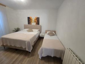 two beds in a room with white walls and wooden floors at Apartments Angela in Primošten +52 photos