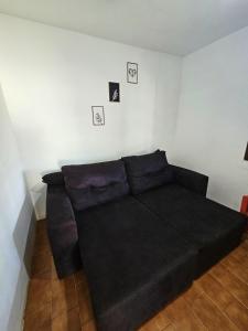 a black couch in a room with pictures on the wall at Casarão entre Cabo Frio e Búzios Piscina Privativa Ar condicionado, Sinuca, Totó, Churrasqueira 4 quartos Wi-Fi 500mb in Cabo Frio