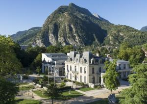 a large white building in front of a mountain at La Pinéa 40 m2 T2 climatisation, tram E et parking in Saint-Égrève
