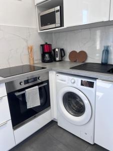 a kitchen with a washing machine and a microwave at La Pinéa 40 m2 T2 climatisation, tram E et parking in Saint-Égrève