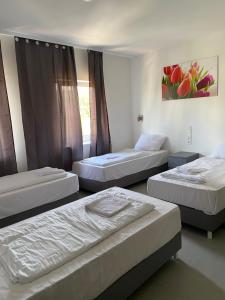 a room with three beds and a painting on the wall at Rosenhof am Main in Offenbach