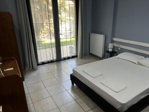 a bedroom with a white bed and a large window at Vicente Apartment in Skala Rachoniou