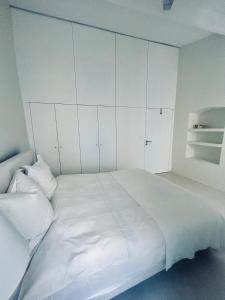a white bedroom with a large bed with white cabinets at L’Ile Rousse les pieds dans l’eau in LʼÎle-Rousse