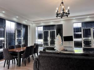 a dining room with a table and chairs and windows at Peaceful Garden Villa in Gabala