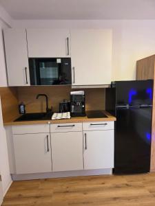 a kitchen with a black refrigerator and white cabinets at Schönes Apartment in Schwäbisch Hall