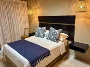 a bedroom with a bed with blue and white pillows at The Suburban Guest House in Bloemfontein