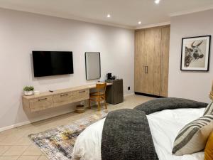 a bedroom with a desk with a tv on the wall at The Suburban Guest House in Bloemfontein