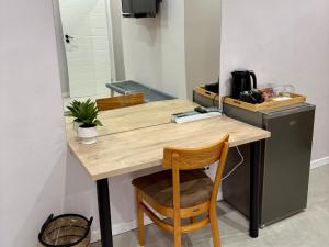 a kitchen with a wooden table with two chairs and a refrigerator at The Suburban Guest House in Bloemfontein