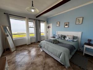 a bedroom with a bed with blue walls and windows at Seaview Sunsets in Gqeberha