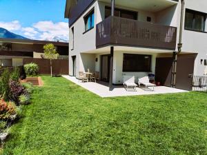 a house with a yard with chairs and a balcony at Apartments LIANA in Postal