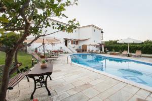a pool with a table and chairs next to a house at Pavlos Maria studios in Skiathos
