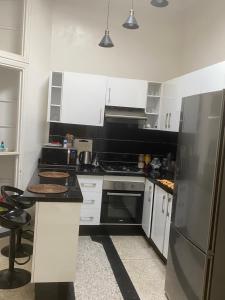 a kitchen with white cabinets and a black refrigerator at Belle Villa in Casablanca