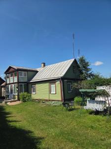 ein grün-gelbes Haus mit einem Picknicktisch im Garten in der Unterkunft Pas tetulę in Anykščiai