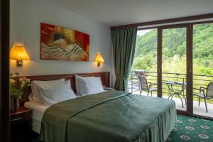 a hotel room with a bed and a balcony at Zan Hotel Voineasa in Voineasa