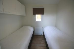 two beds in a small room with a window at Residence de Eese in De Bult