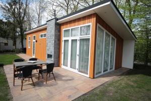 a small house with a table and chairs on a patio at Residence de Eese in De Bult