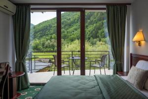 a bedroom with a bed and a balcony with a view at Zan Hotel Voineasa in Voineasa