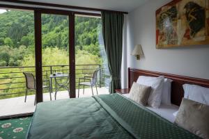 a bedroom with a bed and a balcony with a view at Zan Hotel Voineasa in Voineasa