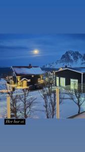 a house with the lights on in the snow at The Dream Factory in Andøya