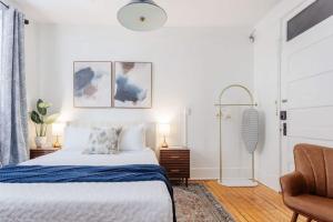 a white bedroom with a bed and a chair at Chic Studio Apartment on Oglethorpe Square in Savannah