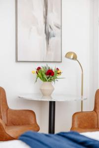 a table with a vase of flowers on it with two chairs at Chic Studio Apartment on Oglethorpe Square in Savannah +32 photos