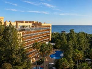 a building with a swimming pool next to the ocean at Aparthotel SunClub Salou in Salou