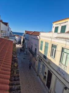 an alley with buildings and a person walking down a street at Casa do Mar & Sesimbra Center View in Sesimbra