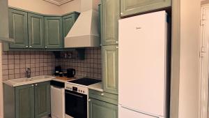 a kitchen with green cabinets and a white refrigerator at Abela Family Hotel in Argassi