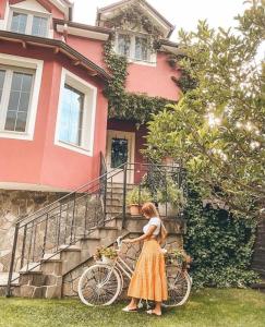 a woman standing next to a bike in front of a house at Tre Bujtinat Gjinar in Elbasan
